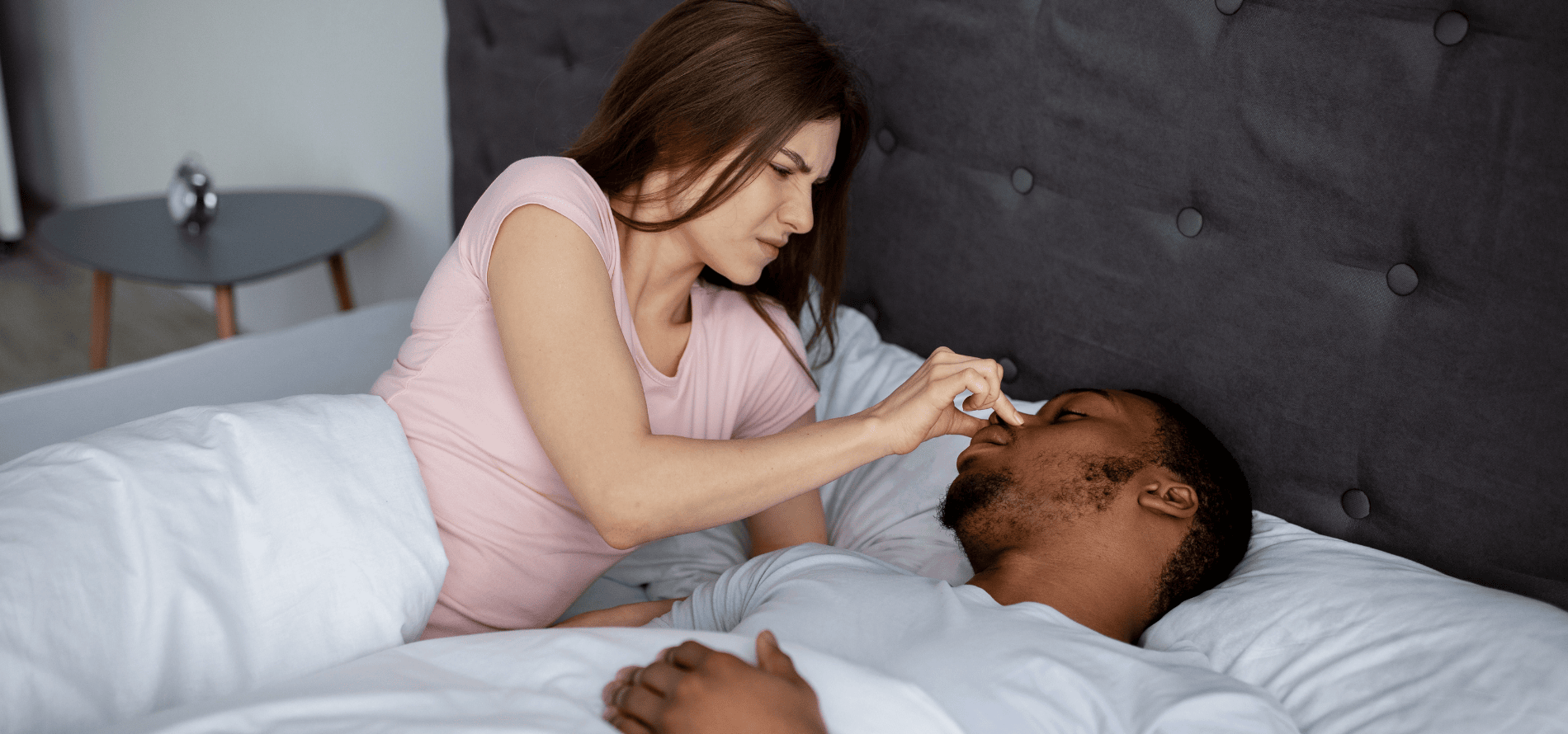 Man sleeping and his partner holding his nose shut